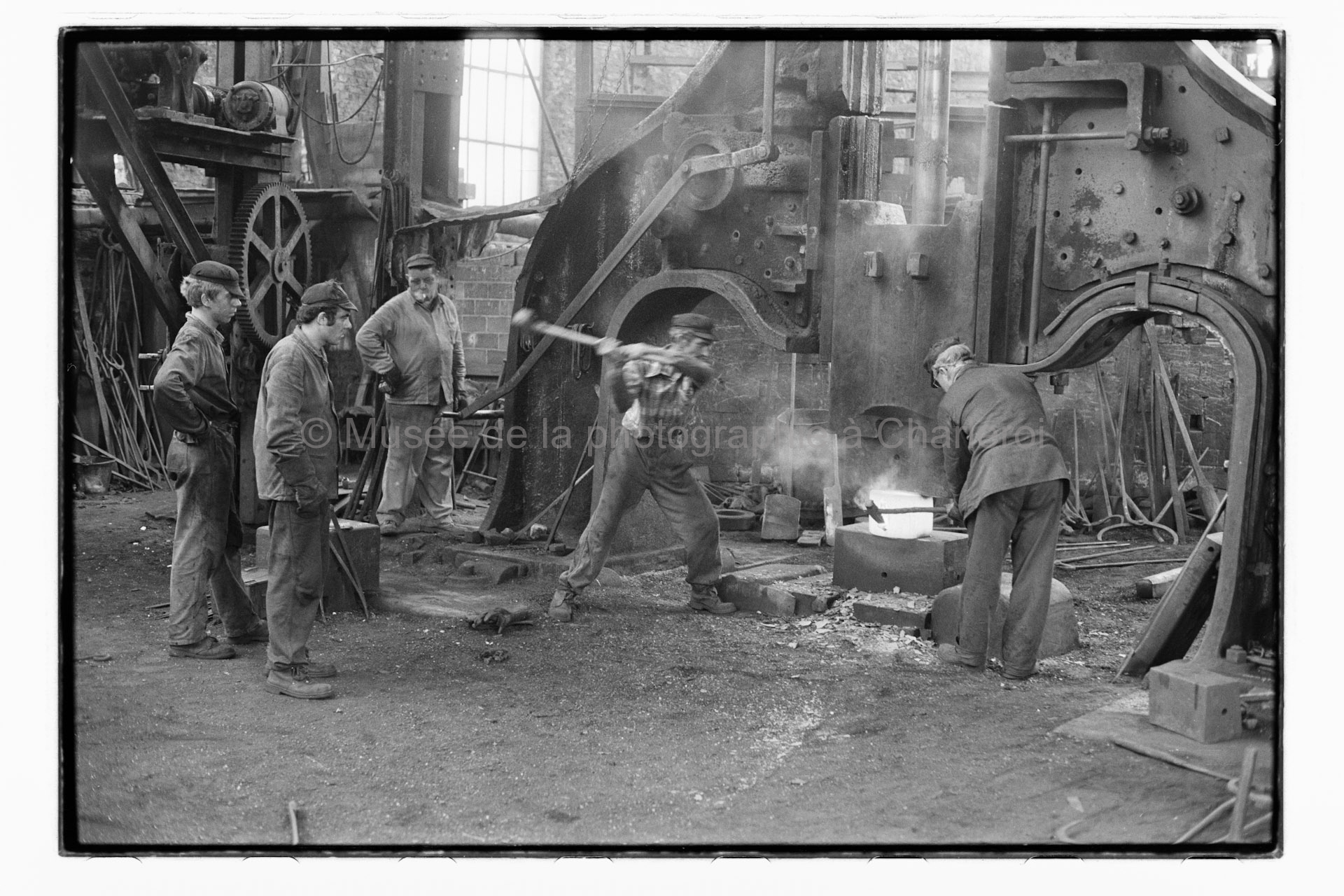 Ouvriers travaillant sur l'affinage d'une pièce métallique